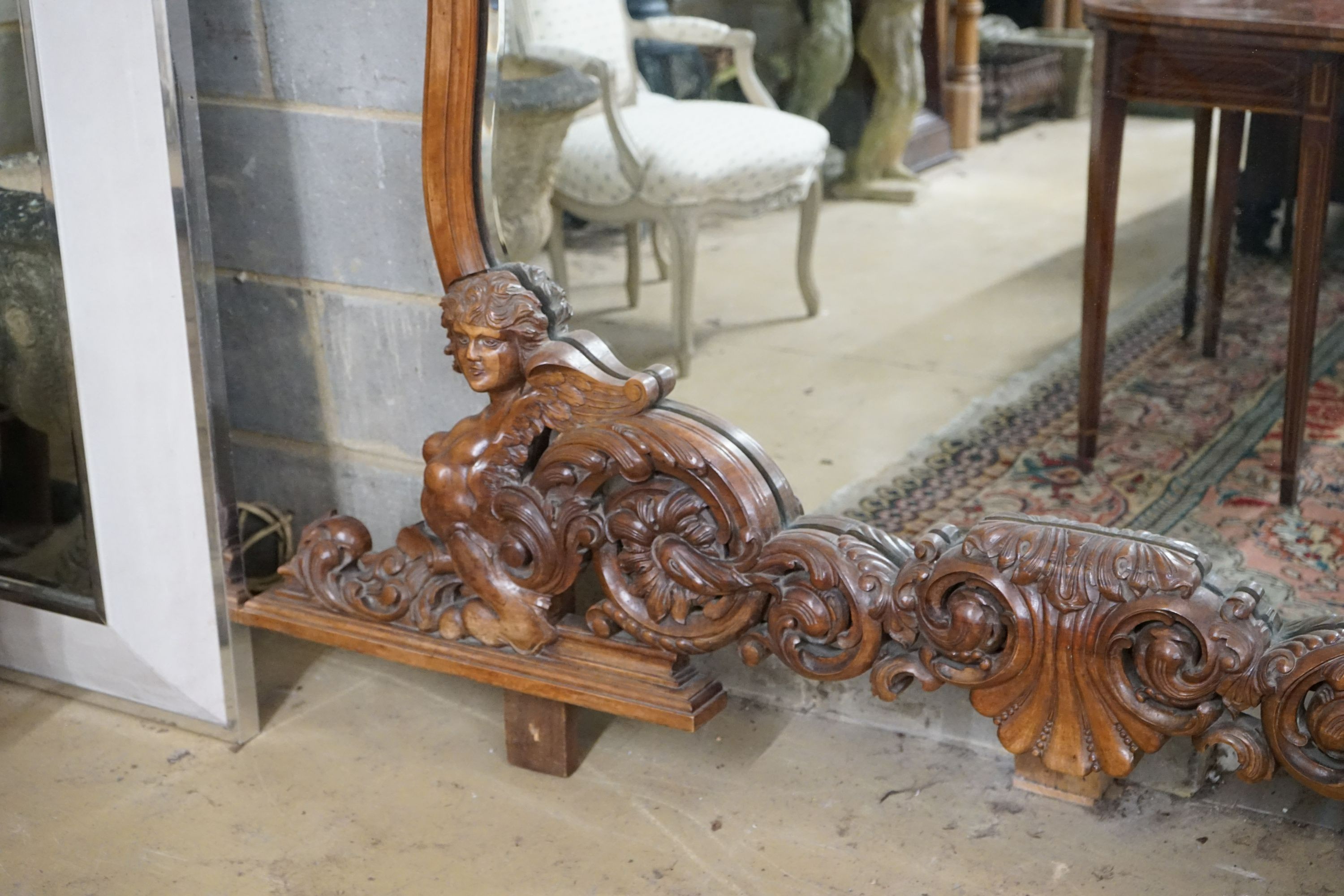 A near pair of Italian style carved walnut overmantel mirrors, decorated with winged figures, scrolls and scallop shells, larger width 200cm, height 152cm